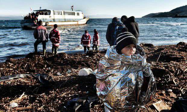 کودکی که در پتوی اضطراری پیچیده شده و همراه با سایر پناهندگان به ساحل جزیره لِسبُس در یونان رسیده است
